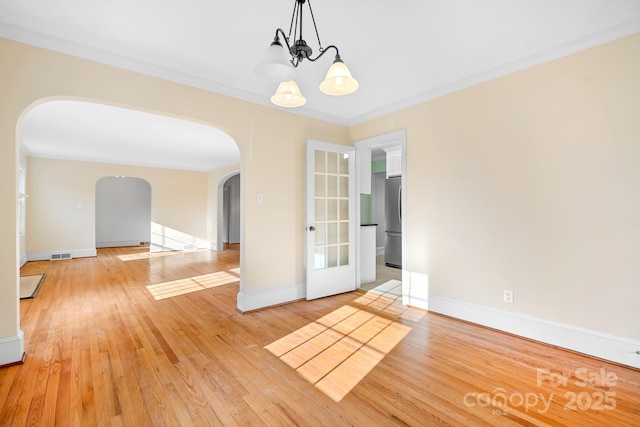 unfurnished room featuring an inviting chandelier, crown molding, and light hardwood / wood-style flooring