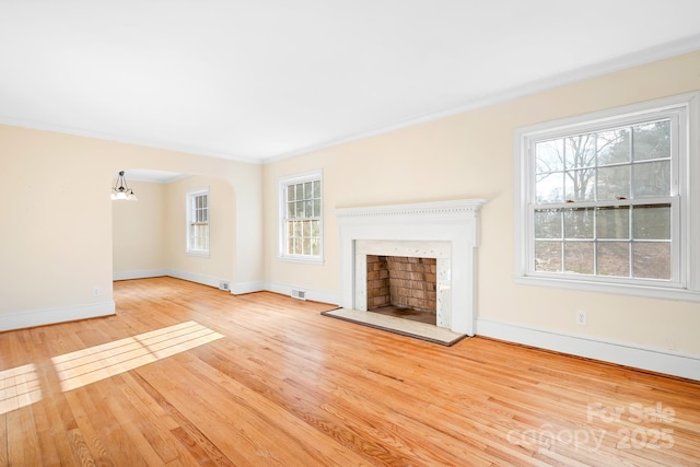 unfurnished living room featuring crown molding, a chandelier, and light wood-type flooring