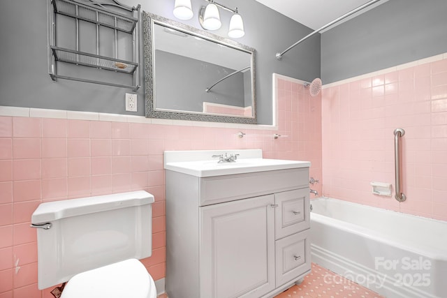 full bathroom featuring vanity, toilet, tiled shower / bath combo, and tile walls