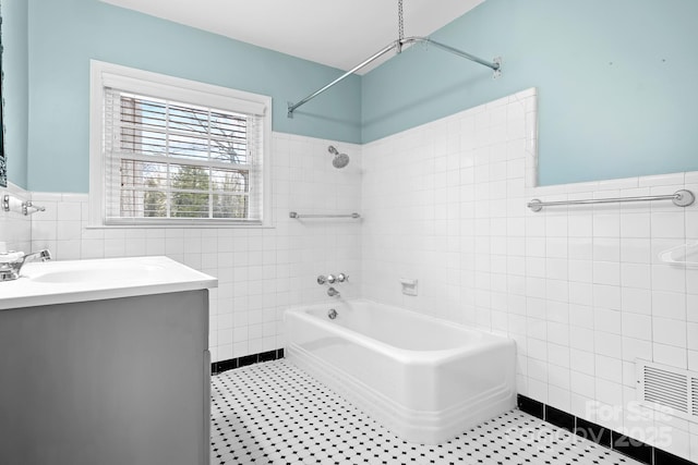 bathroom with tile walls, vanity, and tiled shower / bath