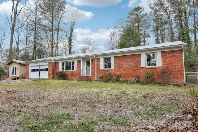 single story home featuring a garage, entry steps, driveway, brick siding, and a front yard