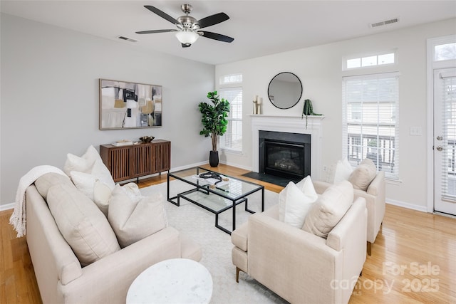 living room with plenty of natural light, light hardwood / wood-style floors, and ceiling fan