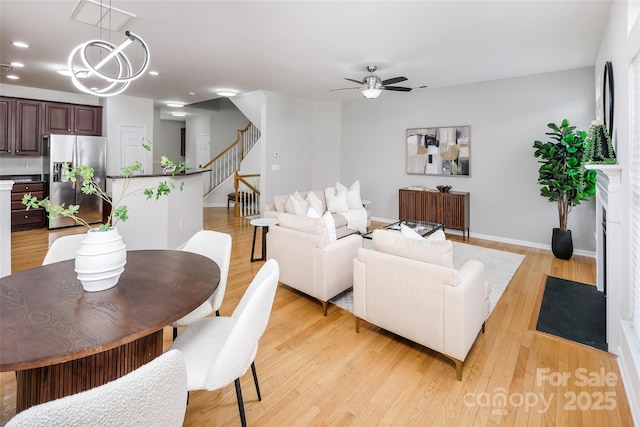 living room with ceiling fan with notable chandelier and light wood-type flooring