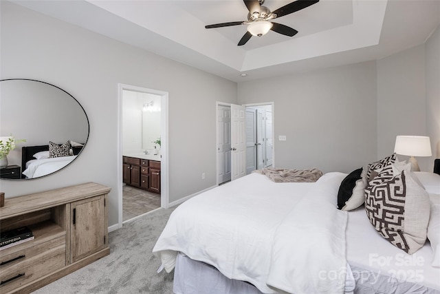 carpeted bedroom with connected bathroom, a raised ceiling, and ceiling fan