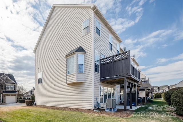 view of home's exterior featuring central AC, a balcony, and a lawn