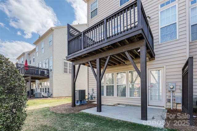 rear view of property featuring a patio, a wooden deck, a lawn, and central air condition unit