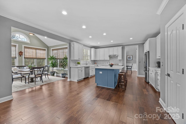 kitchen with a breakfast bar, white cabinetry, backsplash, a center island, and stainless steel appliances