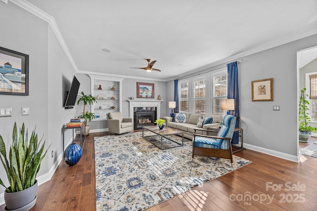 living room with ornamental molding, built in features, dark hardwood / wood-style floors, and ceiling fan