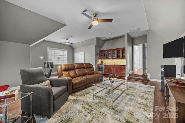 living room featuring lofted ceiling, dark wood-type flooring, ceiling fan, bar, and beverage cooler