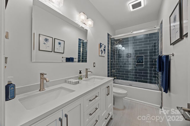 full bathroom featuring toilet, vanity, shower / bath combination with glass door, and hardwood / wood-style floors