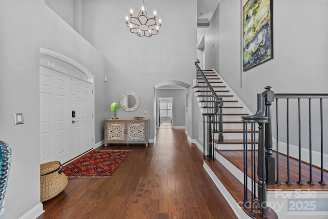 foyer entrance featuring a high ceiling, dark hardwood / wood-style floors, and an inviting chandelier