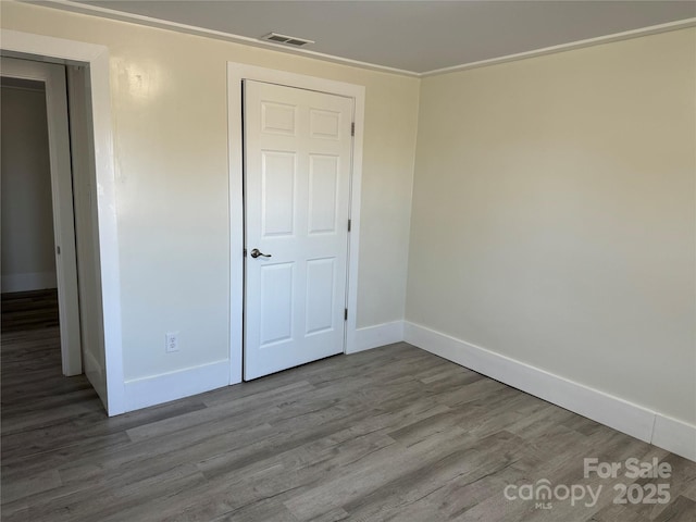 unfurnished bedroom featuring crown molding, a closet, and light wood-type flooring