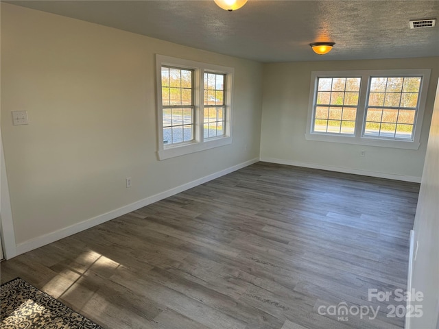 unfurnished room with dark wood-type flooring and a textured ceiling