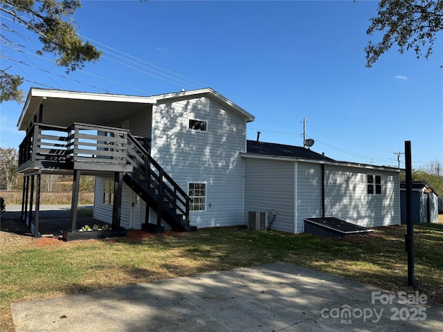 rear view of house featuring a wooden deck, a lawn, and central air condition unit