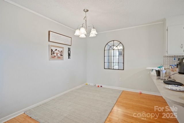 unfurnished dining area featuring hardwood / wood-style floors, a notable chandelier, ornamental molding, and a textured ceiling