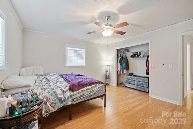 bedroom featuring wood-type flooring, ornamental molding, ceiling fan, and a closet