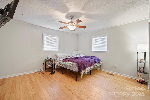 bedroom featuring ornamental molding, light wood-type flooring, a textured ceiling, and ceiling fan