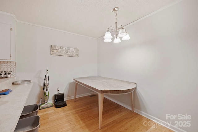 dining space featuring crown molding, a textured ceiling, an inviting chandelier, and light hardwood / wood-style flooring