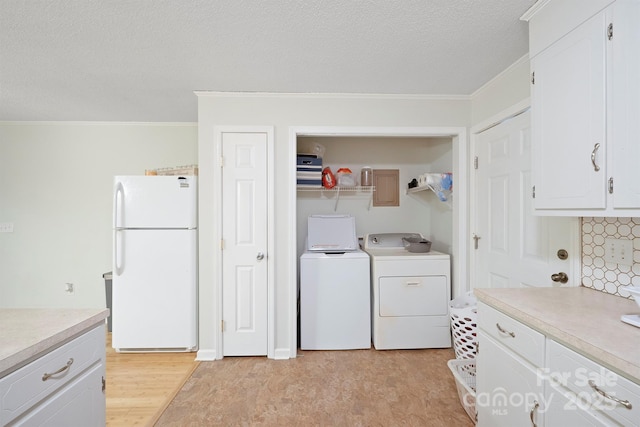 clothes washing area with crown molding, washing machine and clothes dryer, a textured ceiling, and light hardwood / wood-style flooring