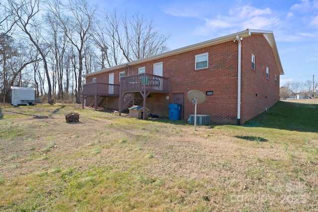 back of property featuring a wooden deck, a yard, and an outdoor fire pit