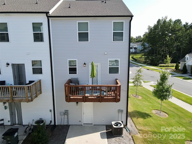 back of property with a balcony, cooling unit, and a lawn