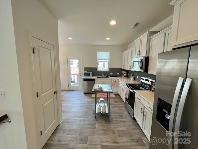 kitchen with tasteful backsplash, appliances with stainless steel finishes, sink, and white cabinets