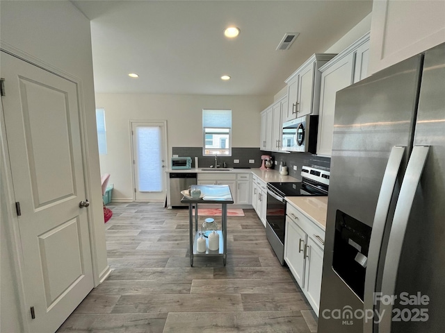 kitchen featuring white cabinetry, appliances with stainless steel finishes, sink, and decorative backsplash