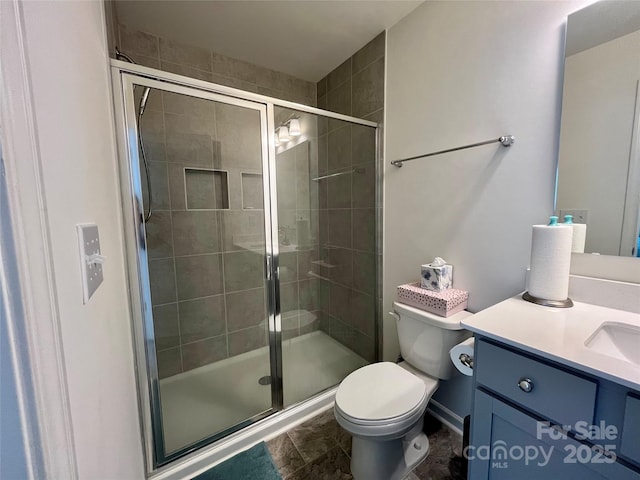 bathroom featuring vanity, a shower with door, and toilet