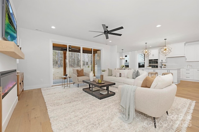 living room featuring ceiling fan, sink, and light hardwood / wood-style floors