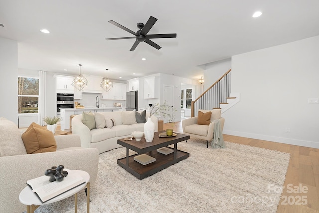 living room featuring ceiling fan, sink, and light hardwood / wood-style floors