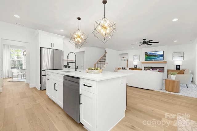 kitchen featuring hanging light fixtures, an island with sink, appliances with stainless steel finishes, and white cabinets