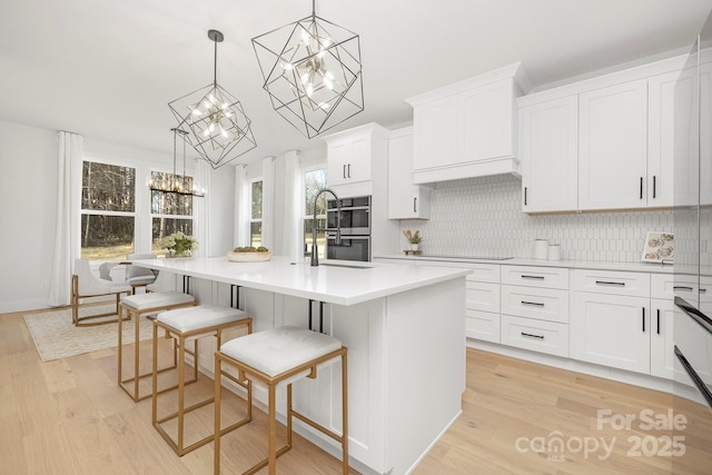 kitchen featuring white cabinetry, hanging light fixtures, and a center island with sink