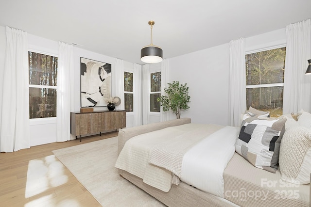 bedroom with multiple windows and light hardwood / wood-style flooring