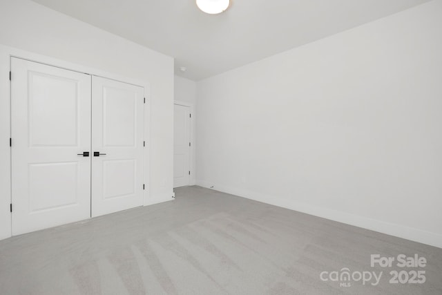 unfurnished bedroom with light colored carpet and a closet