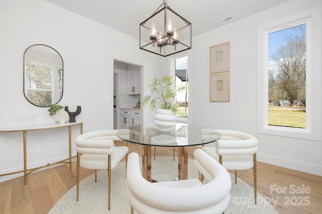 dining room featuring a wealth of natural light, a chandelier, and light wood-type flooring