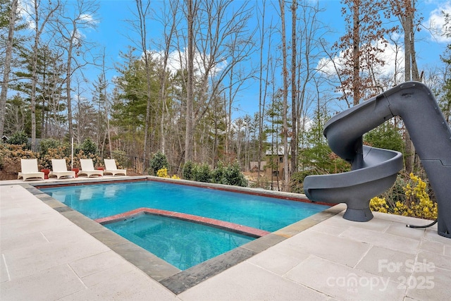 view of pool featuring an in ground hot tub, a water slide, and a patio