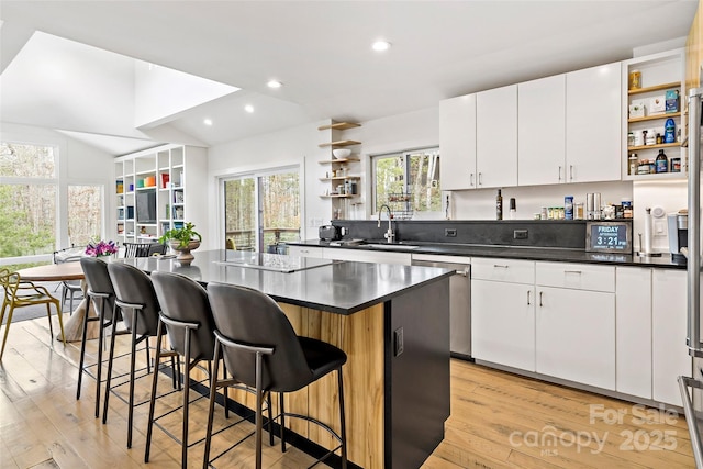 kitchen featuring white cabinetry, sink, a kitchen island, and light wood-type flooring