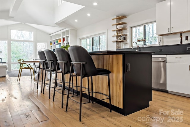 kitchen featuring white cabinetry, vaulted ceiling, a breakfast bar, and plenty of natural light