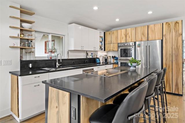 kitchen featuring stainless steel appliances, white cabinetry, a center island, and sink