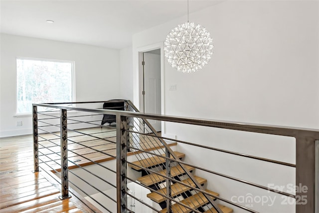 stairs with hardwood / wood-style floors and a chandelier