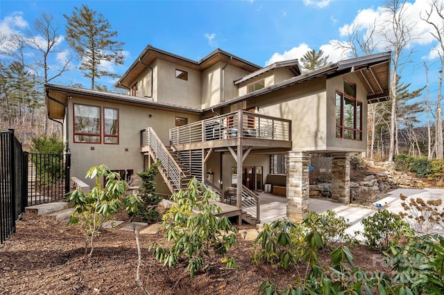 rear view of house featuring a wooden deck and a patio area