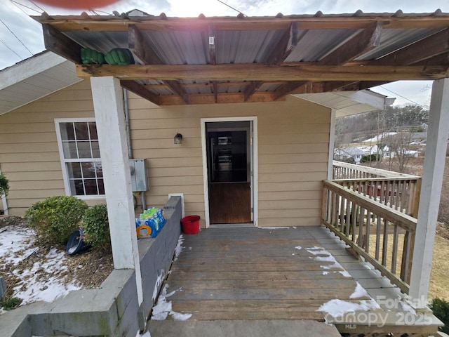 snow covered property entrance with a wooden deck