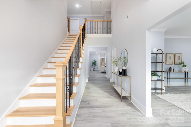 staircase featuring hardwood / wood-style flooring, crown molding, and a high ceiling