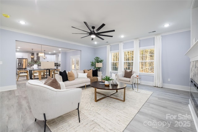 living room featuring ornamental molding, light hardwood / wood-style floors, and ceiling fan