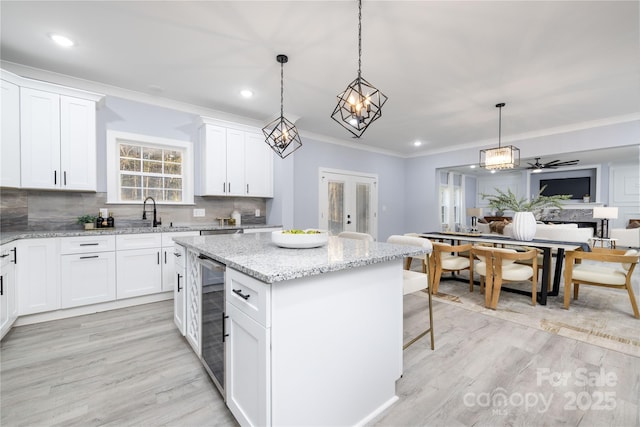 kitchen featuring wine cooler, a center island, hanging light fixtures, white cabinets, and backsplash