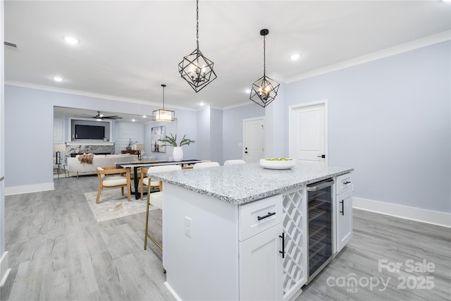 kitchen featuring pendant lighting, beverage cooler, a kitchen island, and white cabinets