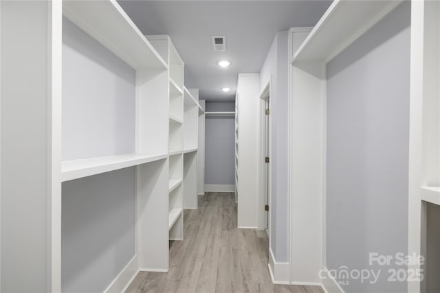 walk in closet with light hardwood / wood-style floors