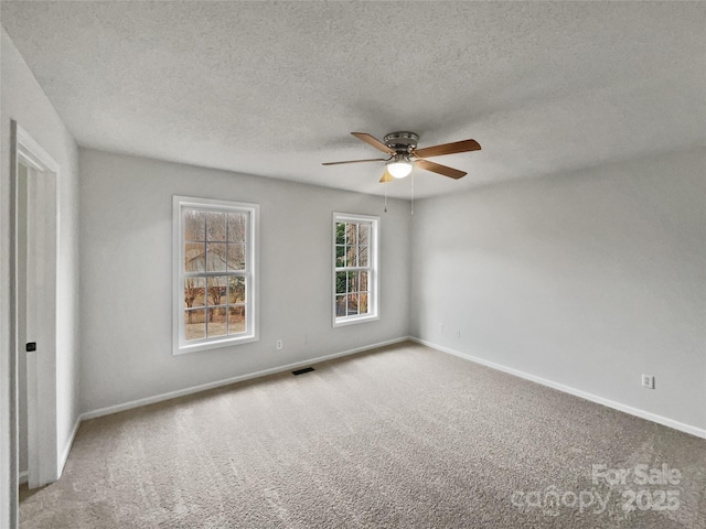 spare room featuring ceiling fan, light carpet, and a textured ceiling