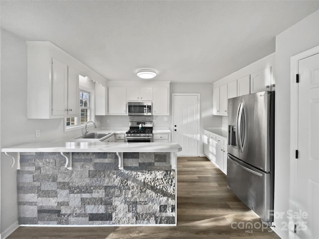 kitchen featuring sink, a breakfast bar area, white cabinets, kitchen peninsula, and stainless steel appliances