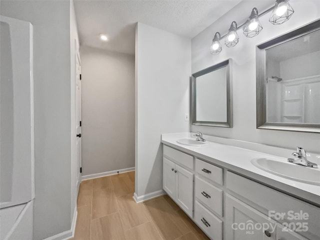 bathroom with vanity, a textured ceiling, and walk in shower